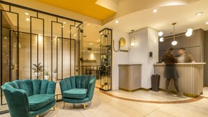 A modern reception area with teal armchairs, a reception desk, and a mirrored wall. - Up Viamonte Hotel (Buenos Aires)