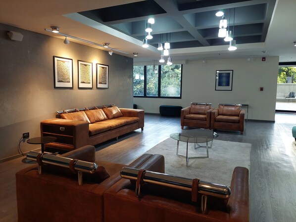 A modern lounge area with leather sofas, a glass coffee table, and pendant lighting.