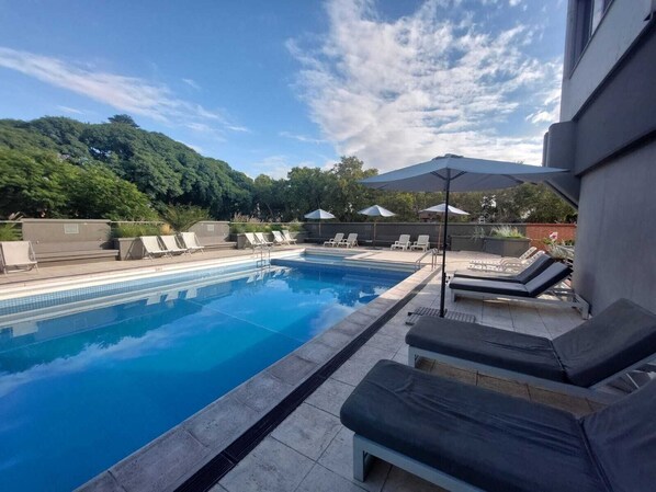 Una piscina al aire libre de temporada, sillones reclinables de piscina