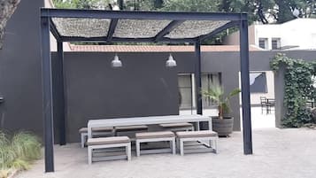 An outdoor seating area with a table and benches under a pergola.