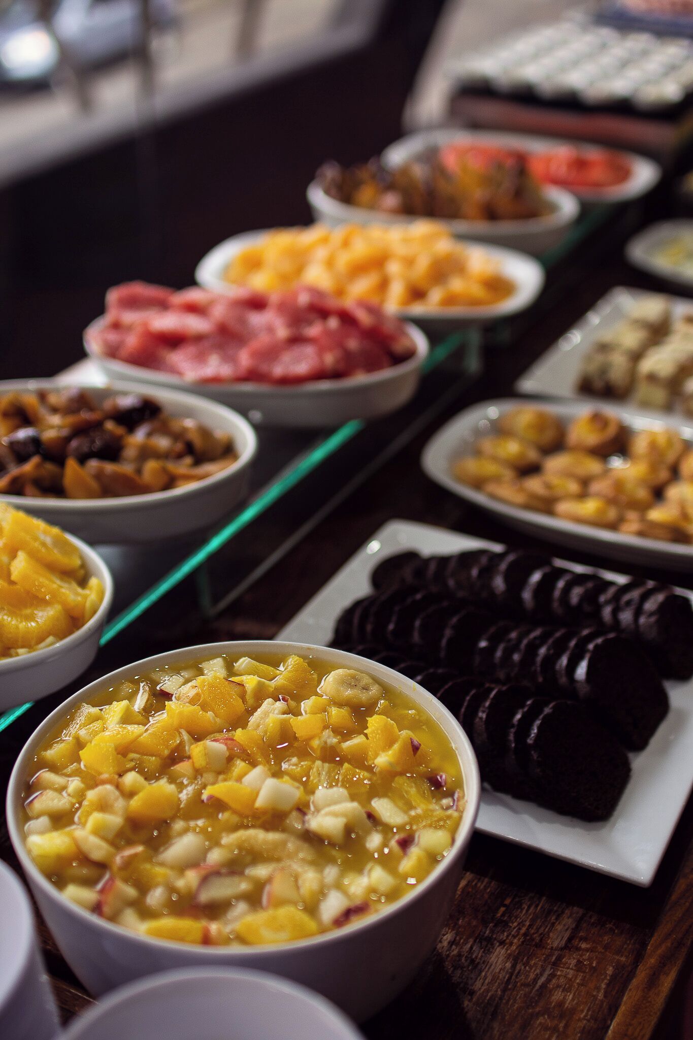 A buffet with various food items including fruits, meats, and desserts.