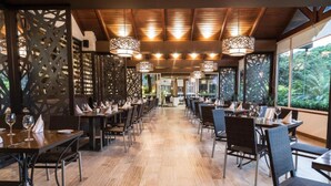 Un restaurant avec un long comptoir, des chaises sombres et des lampes suspendues.