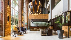 Un hall d’entrée spacieux, doté de hauts plafonds, de grandes fenêtres et d’un lustre moderne.