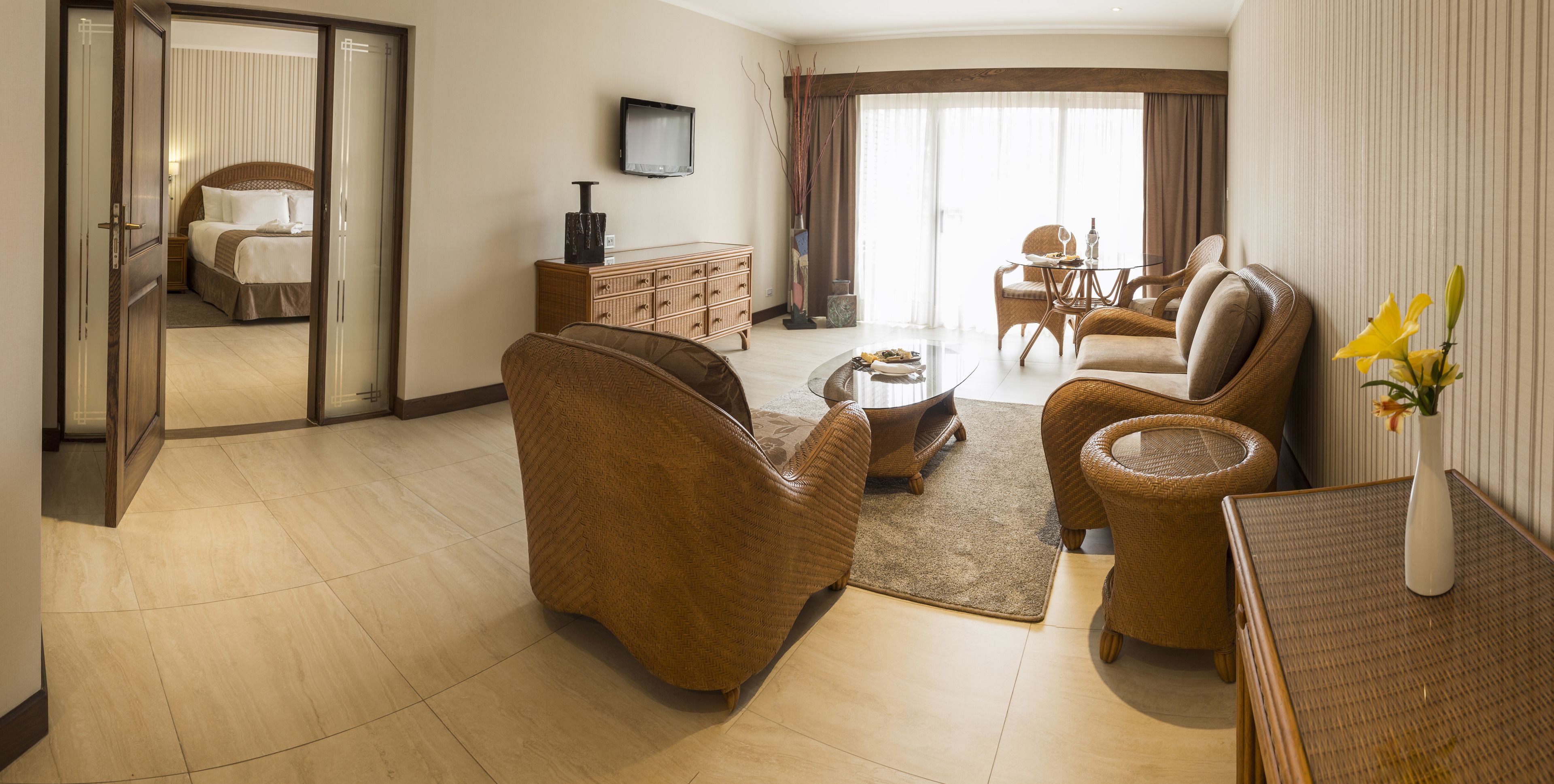 A spacious living room with a sofa, armchairs, a coffee table, and a television.