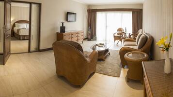 A spacious living room with a sofa, armchairs, a coffee table, and a television.