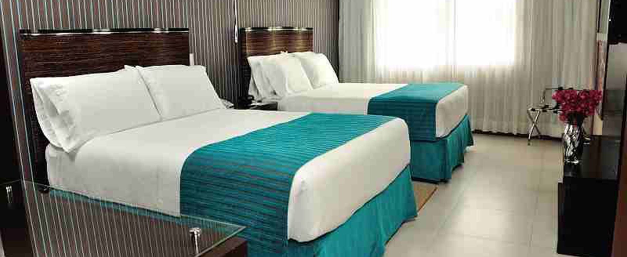 A hotel room with two beds, a nightstand, a desk, and a chair.