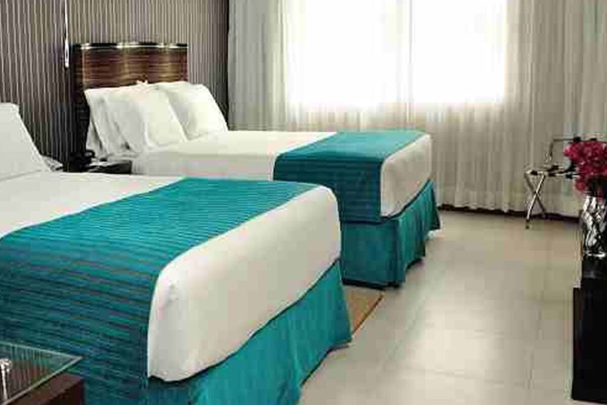 A hotel room with two beds, a nightstand, a desk, and a chair.