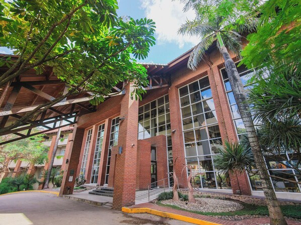 Um edifício com grandes janelas, fachada de tijolos e área de entrada coberta.