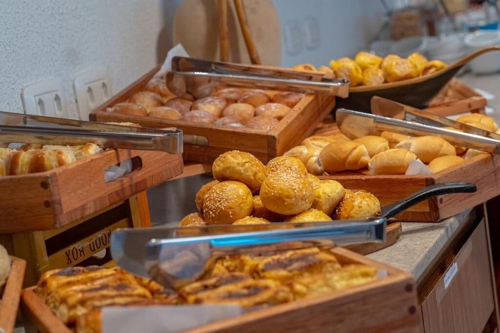 A buffet with various baked goods including bread rolls, pastries, and other baked items.