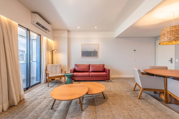 Una sala moderna con un sofá rojo, una mesa de centro de madera y un comedor con una mesa redonda y sillas.