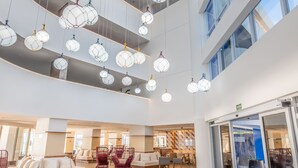 A spacious lobby with a high ceiling, large windows, and hanging spherical light fixtures. - Novotel Salvador Rio Vermelho (Salvador)