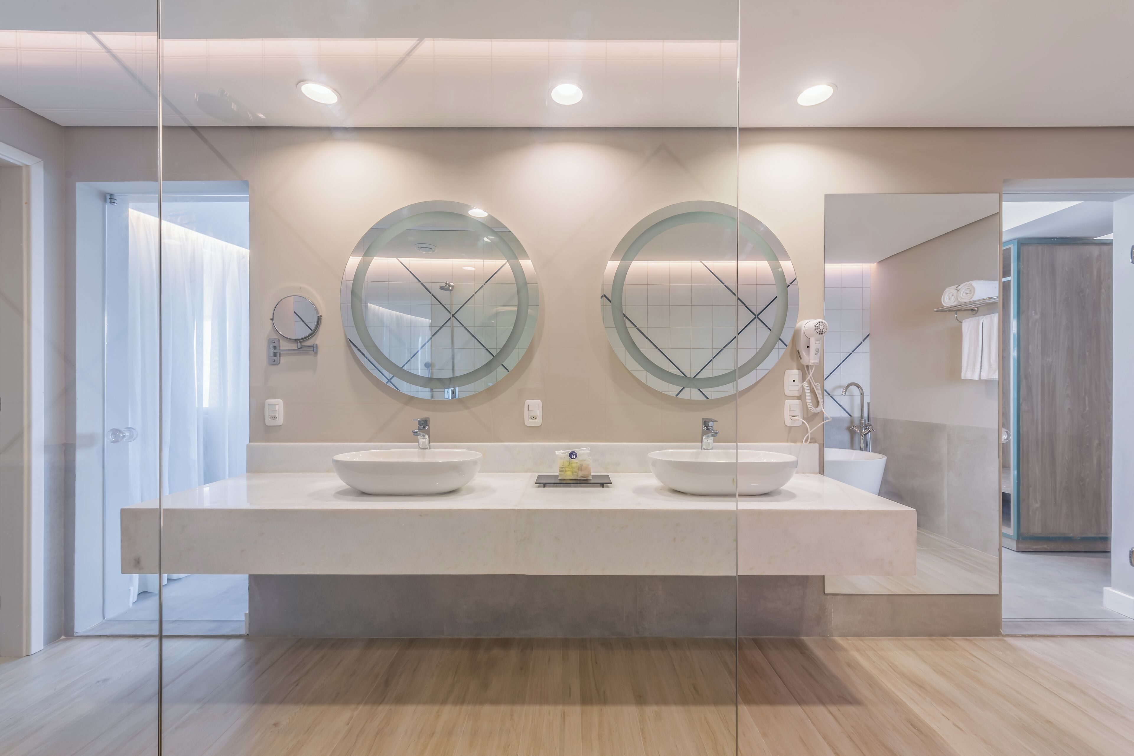 Un baño moderno con dos lavamanos, un espejo grande y una cabina de ducha de vidrio.