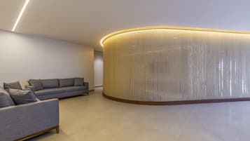 Un interior moderno con un sofá gris, una pared cilíndrica con textura y un diseño limpio y minimalista.