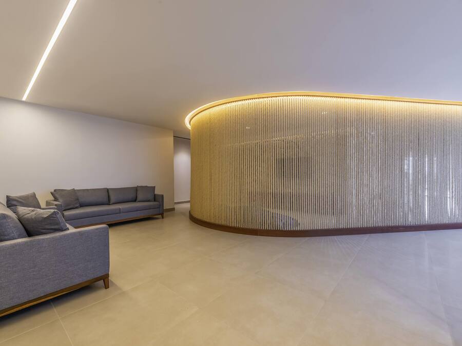 Un interior moderno con un sofá gris, una pared cilíndrica con textura y un diseño limpio y minimalista.
