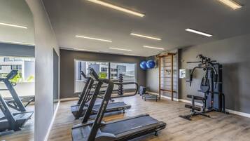 Academia com esteiras, bolas de exercício e barra fixa.