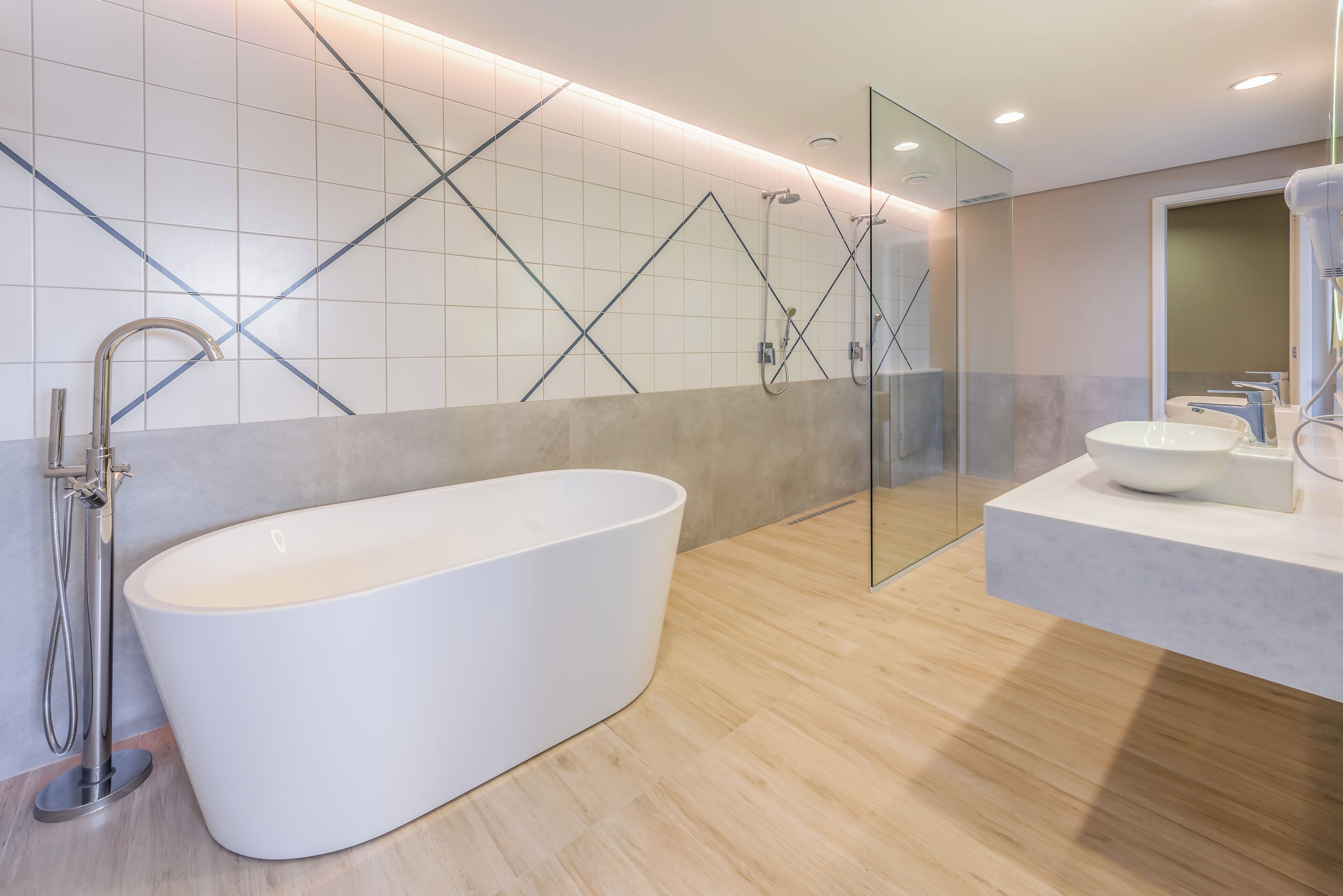 Un baño moderno con una bañera independiente, una ducha con mampara de vidrio y un lavamanos.