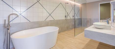 Un baño moderno con una bañera independiente, una ducha con mampara de vidrio y un lavamanos.