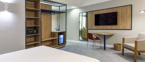 Una habitación de hotel moderna con una cama, un escritorio, una silla, un televisor y un armario con estantes.