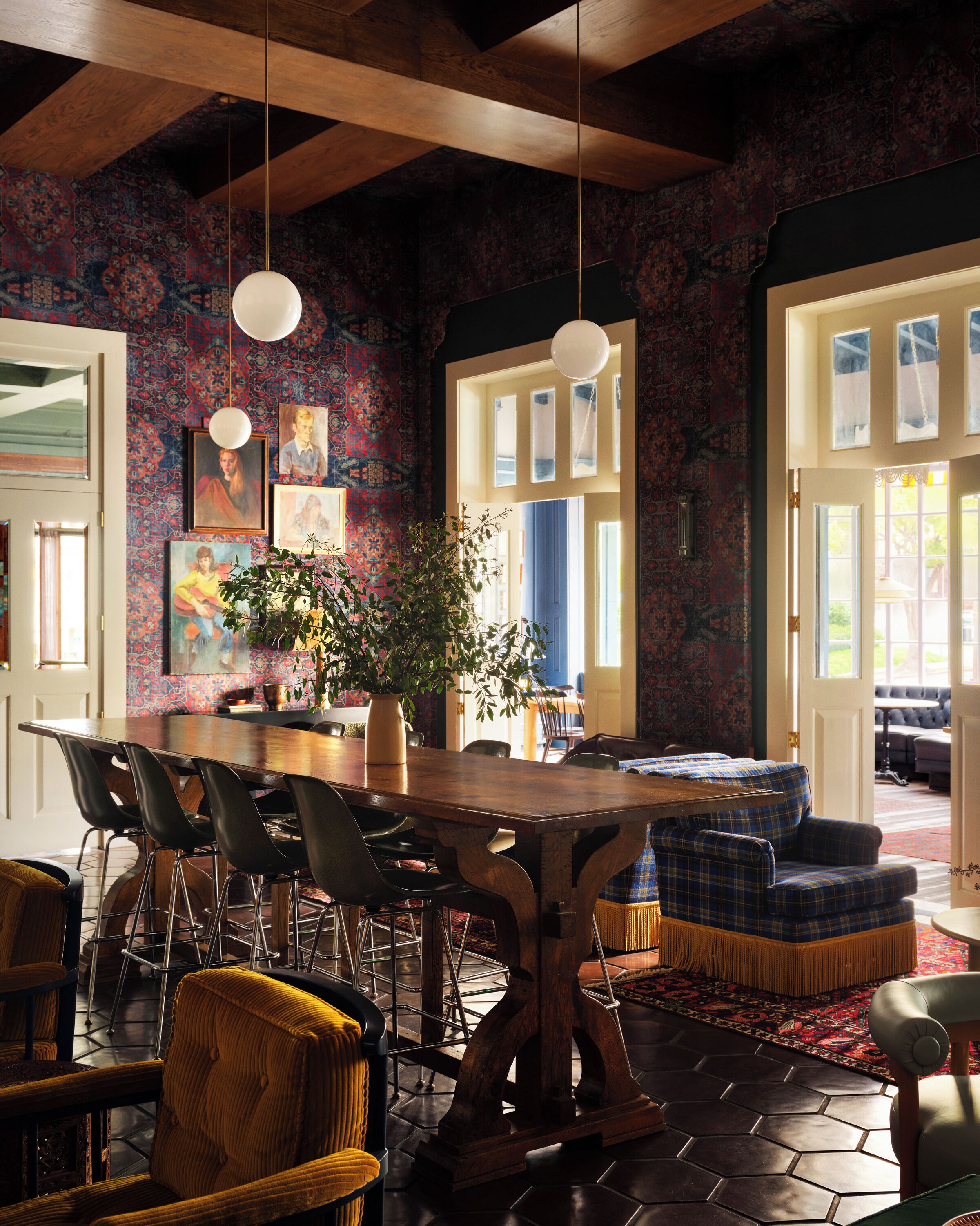Ein Essbereich mit Holztisch und -stühlen, einem Blumentopf und einer Wand mit Muster.