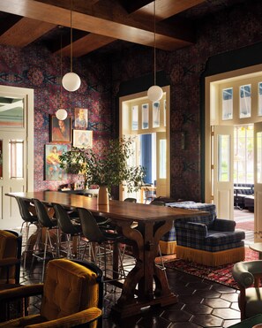 A dining area with a wooden table and chairs, a potted plant, and a patterned wall. - Graduate by Hilton Berkeley (Berkeley)