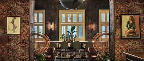 Um interior tradicional com paredes estampadas, uma área de jantar com cadeiras e mesa, e um grande candelabro globo.