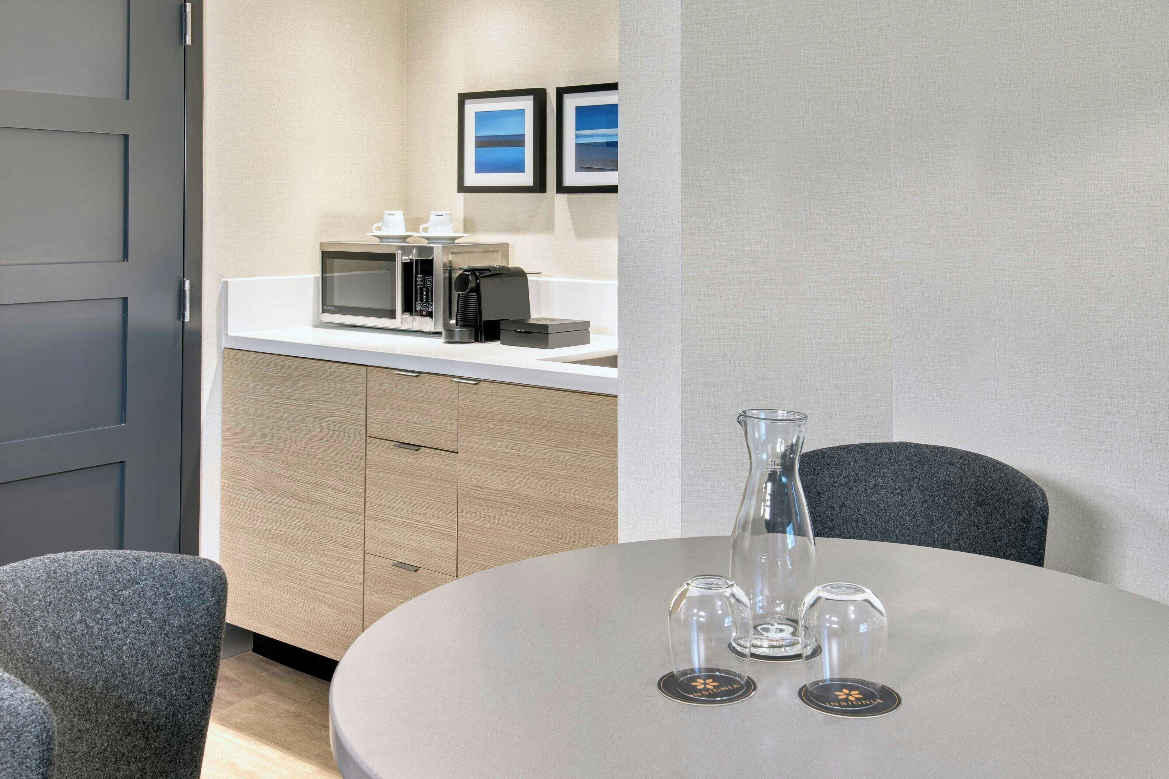 Une chambre d’hôtel moderne avec une table à manger ronde, une machine à café et un four à micro-ondes posés sur le comptoir.