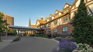 A hotel entrance with a covered walkway, brick facade, and surrounding greenery.