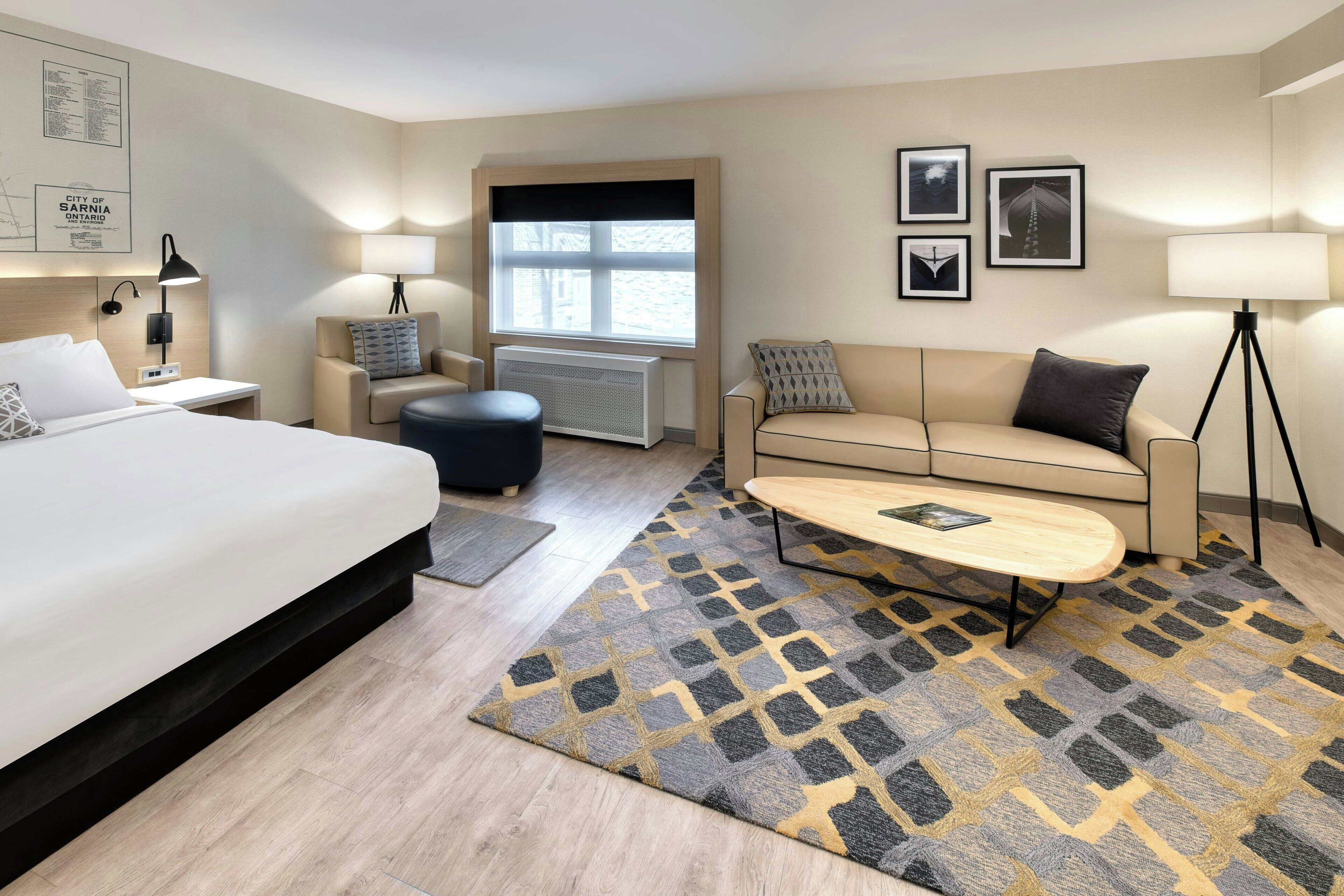 Una habitación de hotel con cama, sofá, mesa de centro, escritorio y ventana.