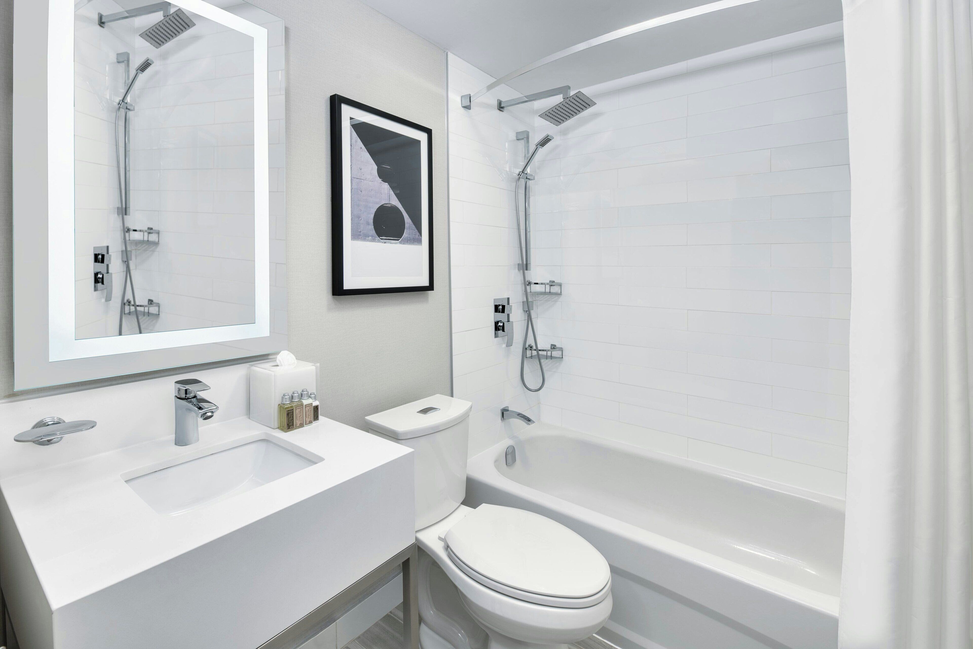 Un baño moderno con lavamanos, inodoro y bañera blancos.