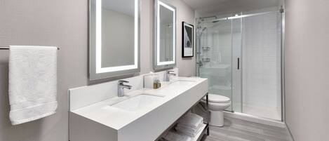 A modern bathroom with two sinks, a toilet, and a glass shower enclosure.