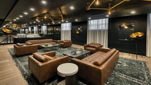 A modern lounge area with leather sofas, a coffee table, and a bar area with stools. - The Insignia Hotel, Sarnia, a Tribute Portfolio Hotel (Sarnia)