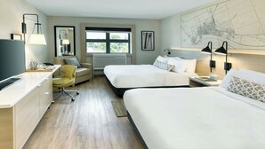 A hotel room with a bed, a desk, a chair, and a large window.