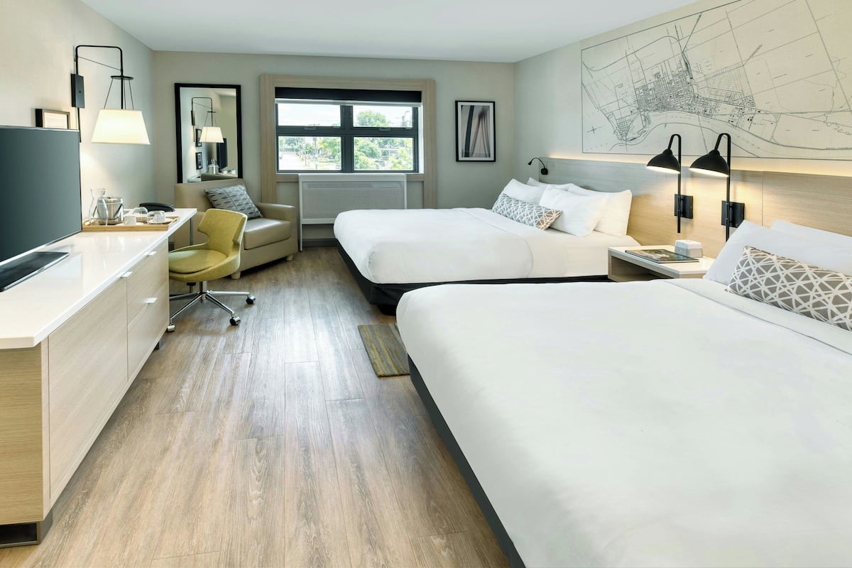 A hotel room with a bed, a desk, a chair, and a large window.