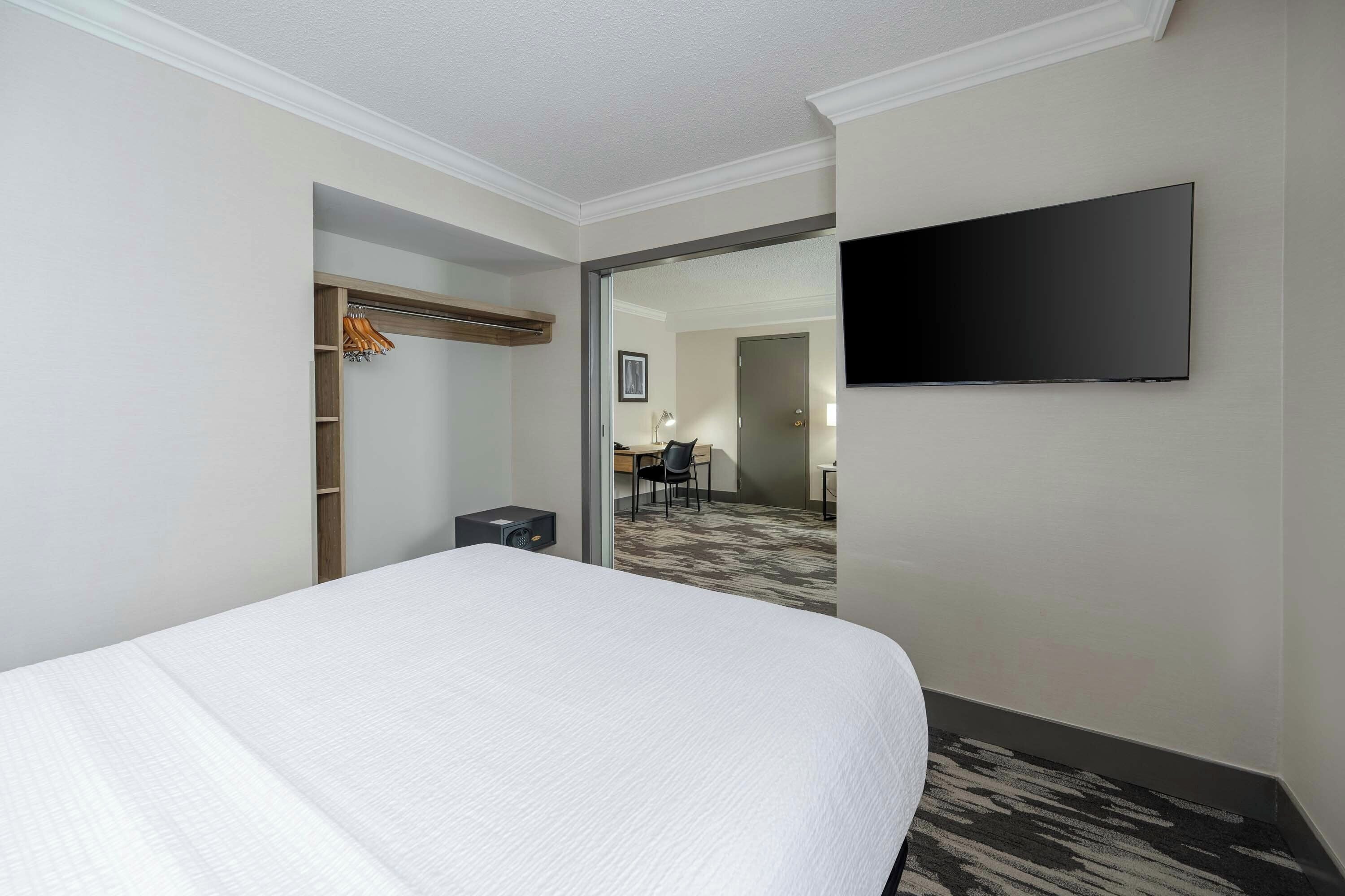 A hotel room with a large bed, a television mounted on the wall, and a walk-in closet.