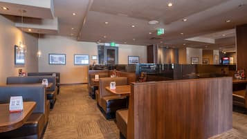 A modern restaurant with booths and tables, a wooden counter, and framed pictures on the walls.