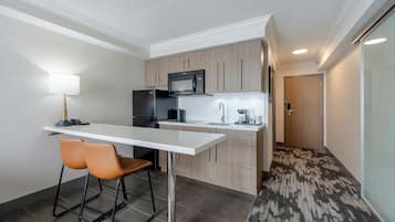 A compact kitchen with a microwave, refrigerator, and a small dining area with two chairs.