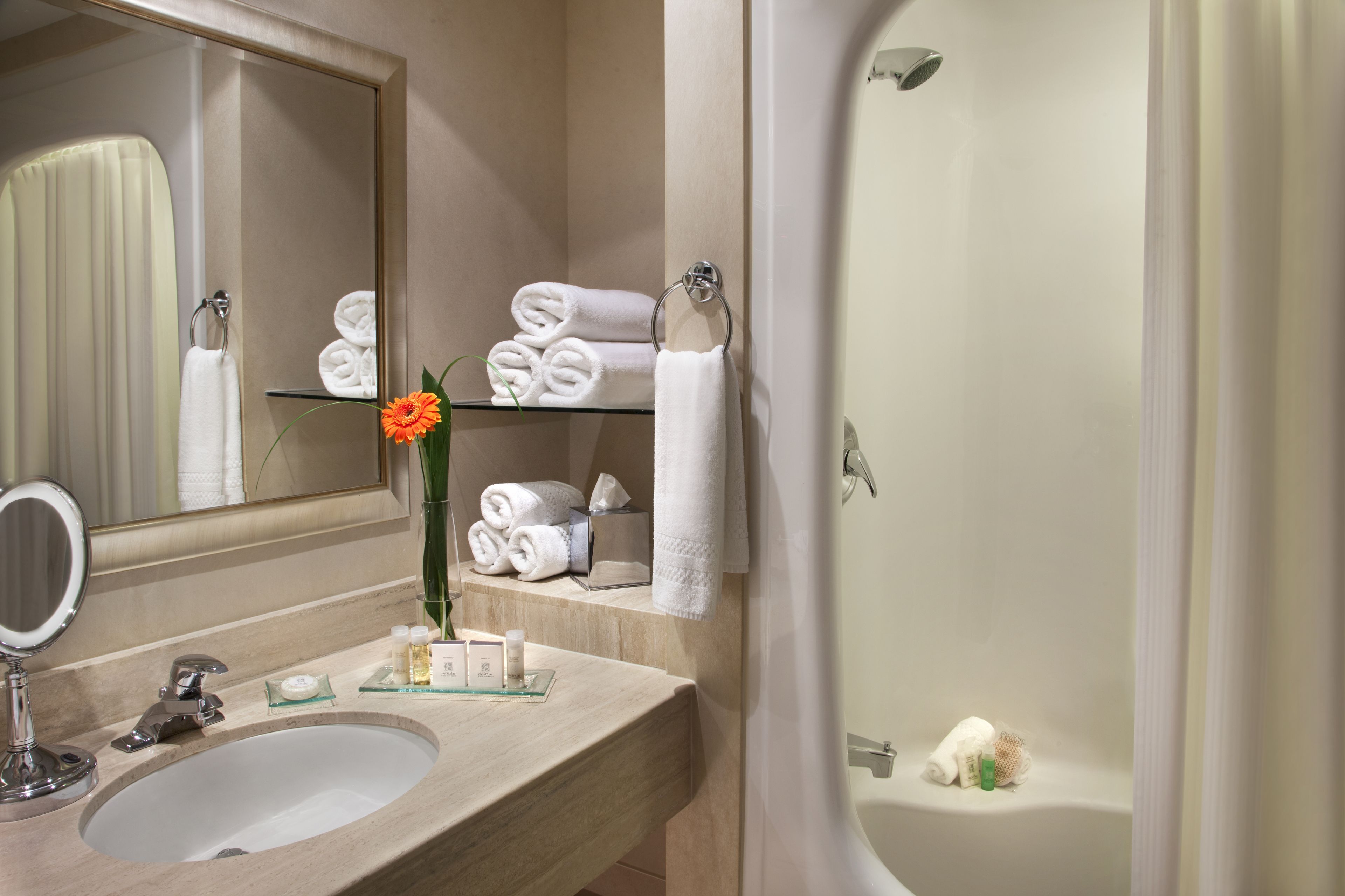 A bathroom with a sink, mirror, and shelves holding towels.