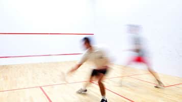 A squash court with a wooden floor and red boundary lines.