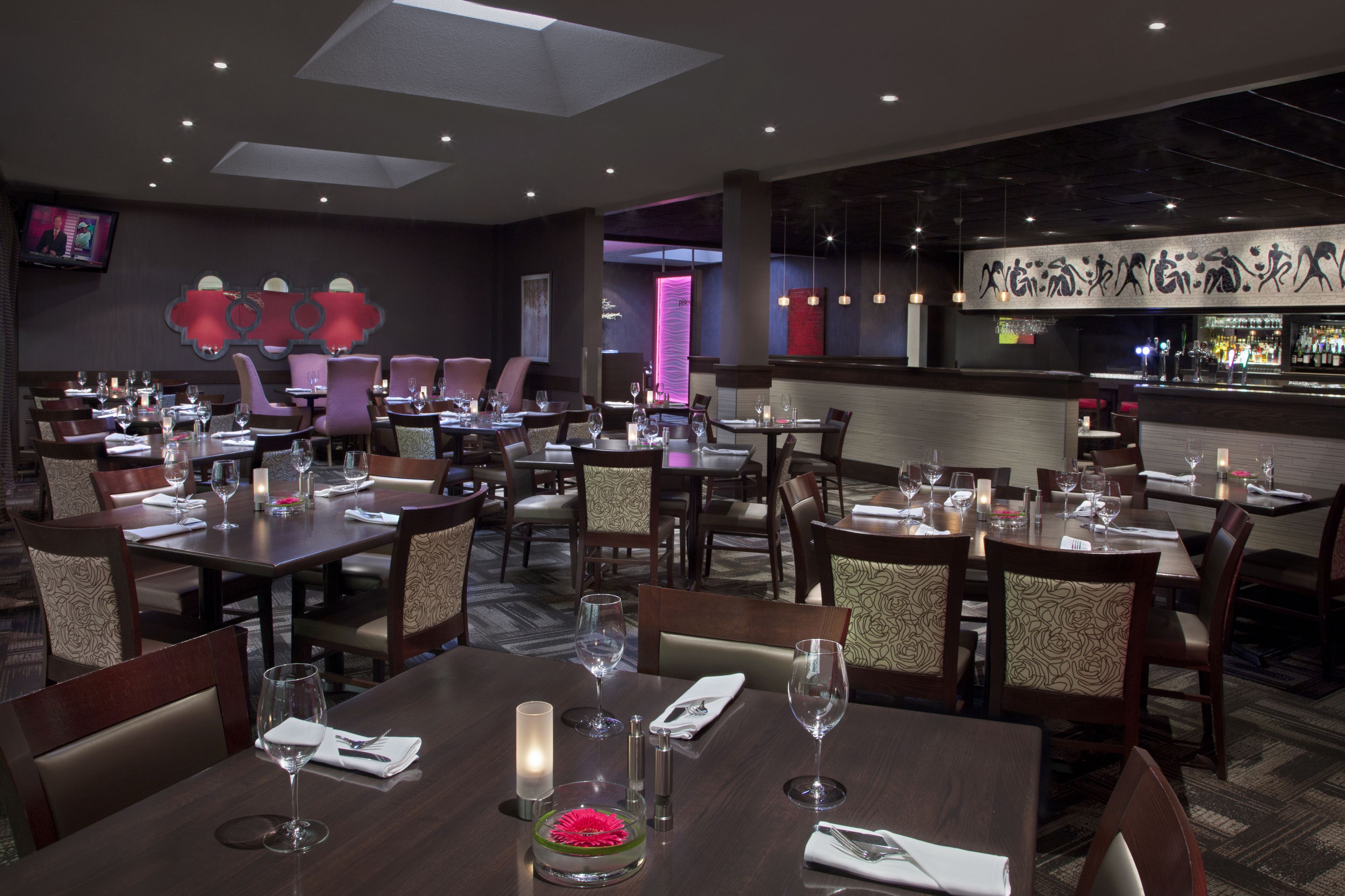 A restaurant with multiple dining tables, chairs, and a bar area.