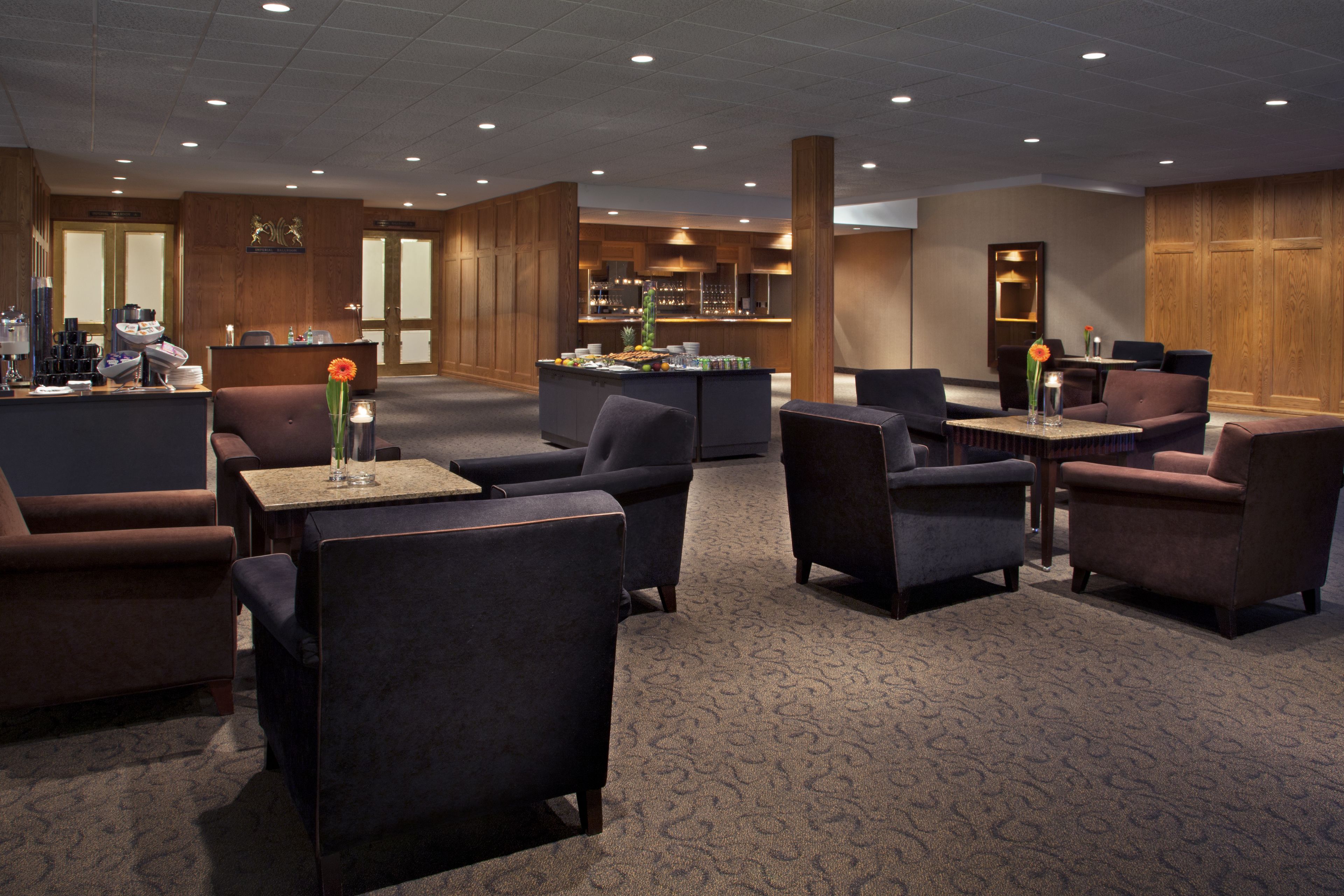 A hotel lobby with seating areas, a reception desk, and a bar/lounge area.