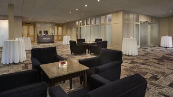 A hotel lobby with a reception desk, seating area, and large windows.