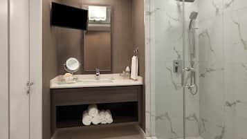 A modern bathroom with a vanity, mirror, towel rack, and a glass-enclosed shower area.