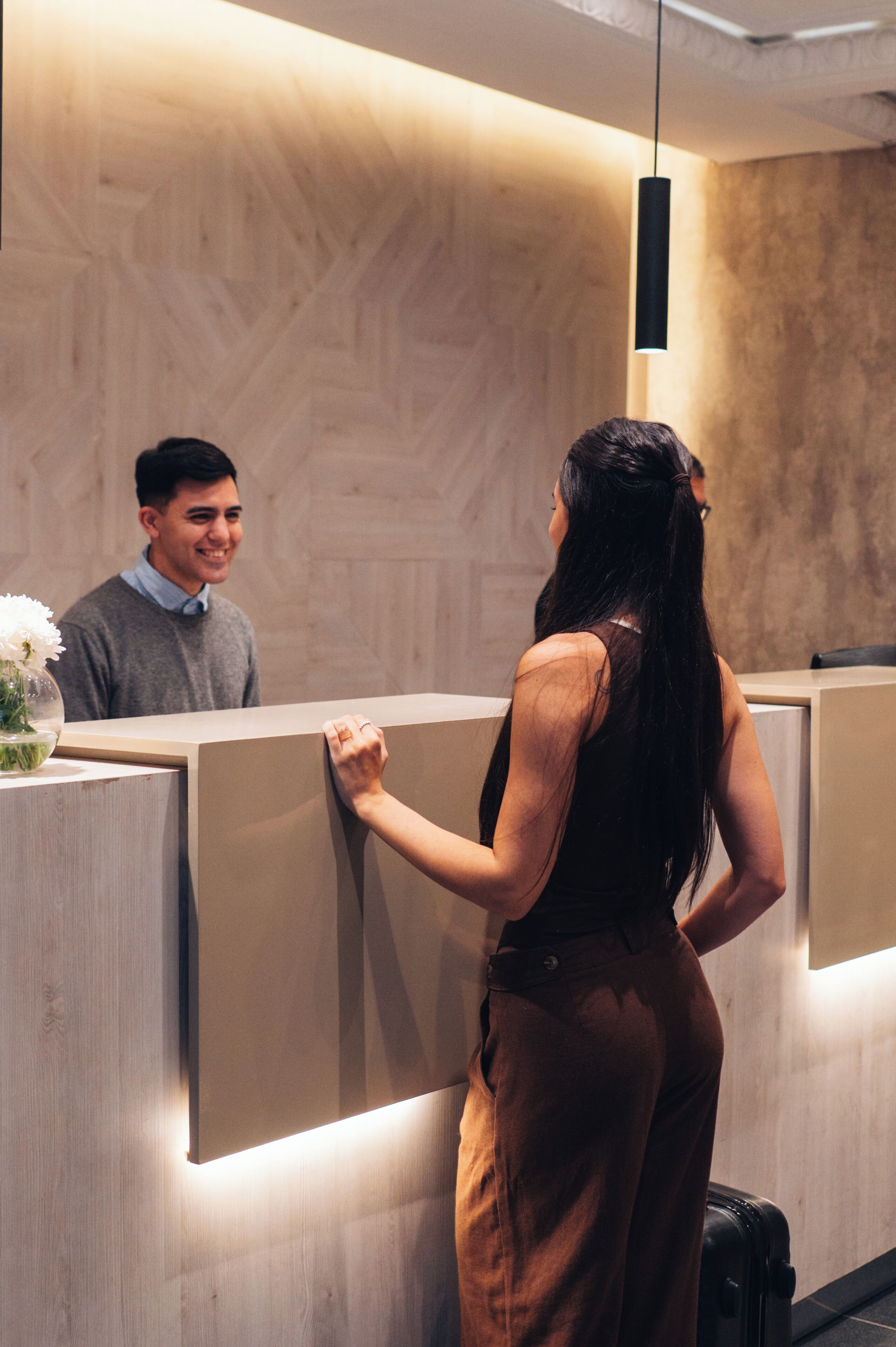 Un área de recepción con paneles de madera y una lámpara colgante moderna.