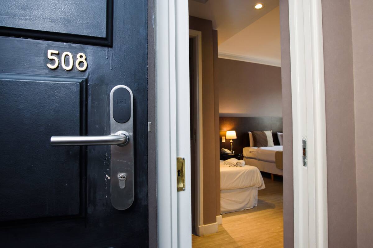 A hotel room with a bed, a bedside table, and a lamp.