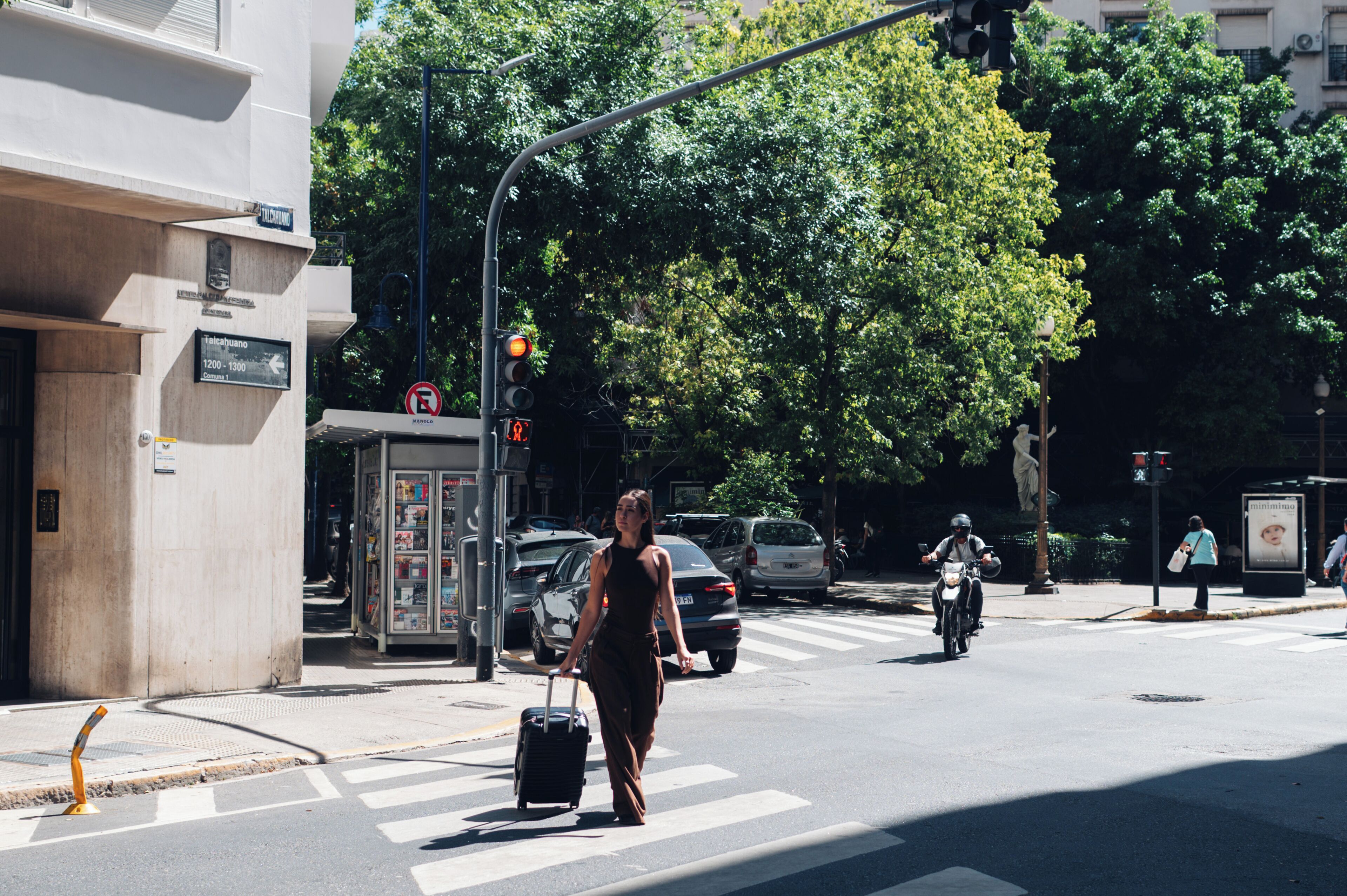 Vista de una calle con un paso de peatones, una parada de autobús y un edificio con un letrero.