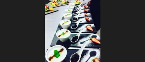 Una mesa con diferentes platos, incluyendo tazones de yogur con ingredientes y rodajas de fruta.