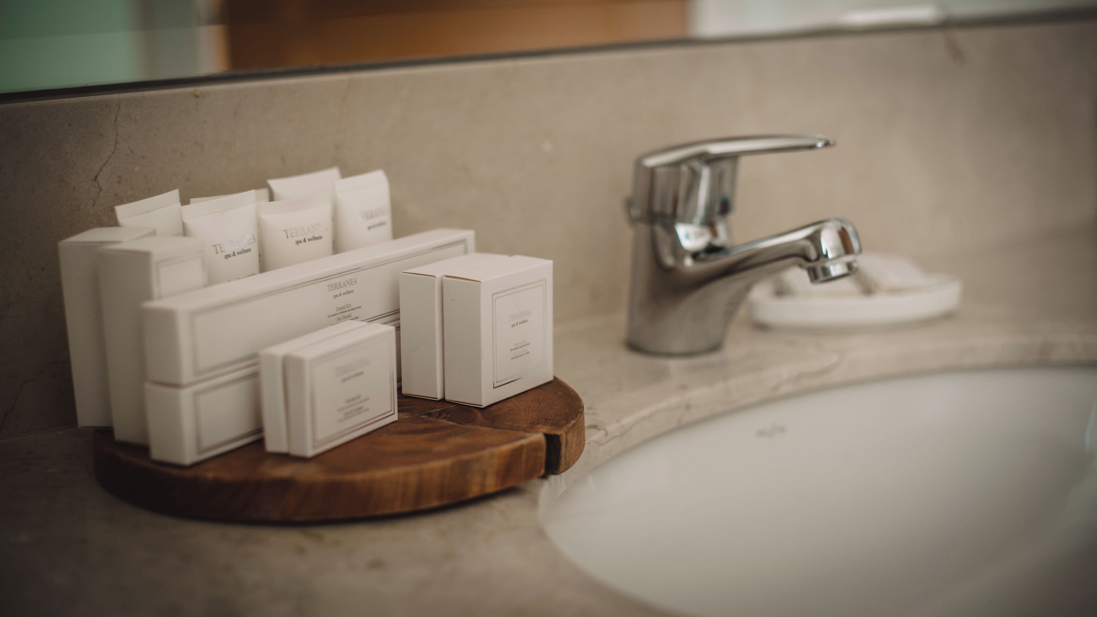 A bathroom with a wooden soap dish holding several white boxes labeled 'Terranea spa & wellness'.
