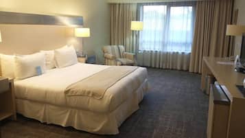 A hotel room with a large bed, two bedside tables, a chair, a desk, and a TV.