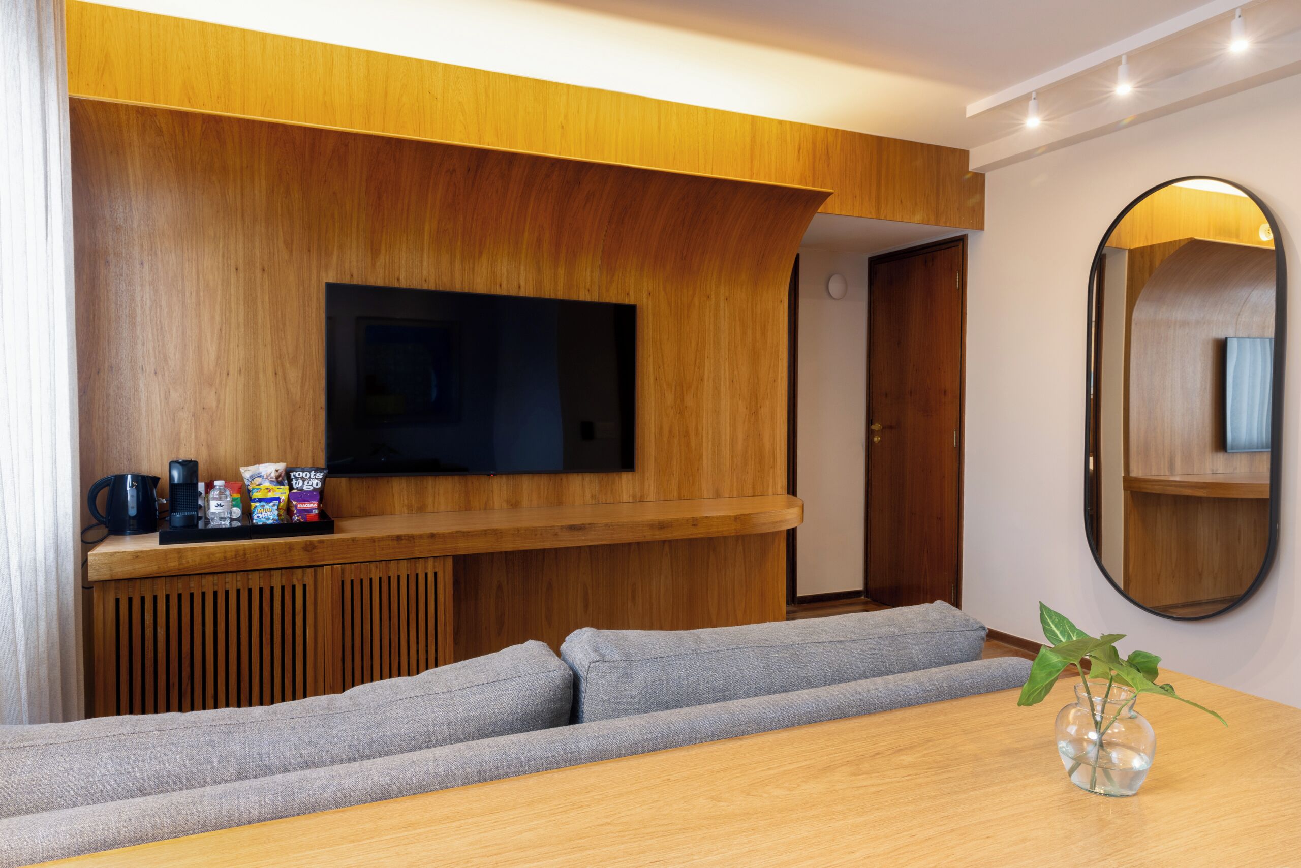 Una sala moderna con una pared de acento de madera, un televisor de pantalla plana, un sofá, una mesa de centro y una planta pequeña.