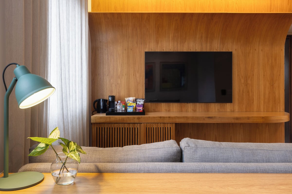A modern living room with a sofa, a coffee table, a lamp, and a flat-screen TV mounted on a wooden wall.